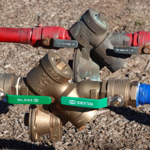 A backflow fixture on a water service line near dirt