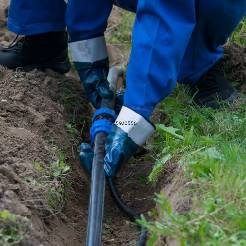 A plumbing laying a new black water service line in a trench