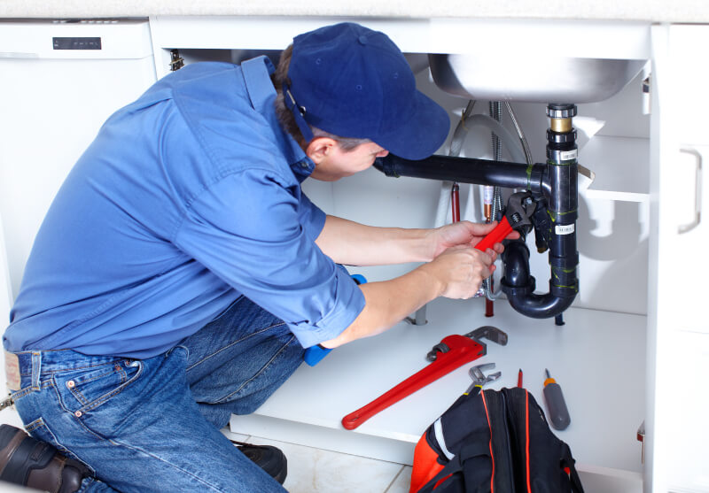 A male plumber working on sink plumbing