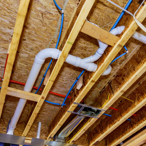 A sewer drain and water pipes exposed in the ceiling