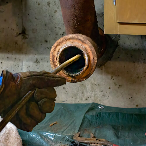 A plumber cabling a sewer drain with safety gloves